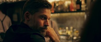 Movie still from “A Taste of Hunger” (2021), directed by Christoffer Boe – A person sitting in a room; Close Up shot, Over the shoulder angle