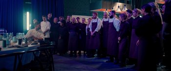 Movie still from “A Taste of Hunger” (2021), directed by Christoffer Boe – A group of people standing in front of a microphone; Wide shot, High angle