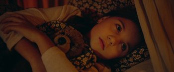 Movie still from “A Taste of Hunger” (2021), directed by Christoffer Boe – A young girl laying in bed with a teddy bear; Close Up shot, High angle