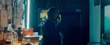 Movie still from “A Taste of Hunger” (2021), directed by Christoffer Boe – A woman standing in a room with a hanging object in front of her face; Medium shot, Low angle