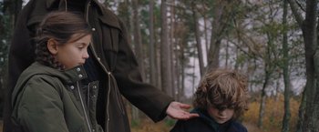 Movie still from “A Taste of Hunger” (2021), directed by Christoffer Boe – A woman holding the hand of a boy in the woods; Medium shot, Over the shoulder angle