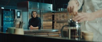 Movie still from “A Taste of Hunger” (2021), directed by Christoffer Boe – A woman sitting in front of a mirror in a kitchen; Medium shot, Low angle