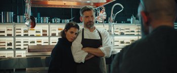 Movie still from “A Taste of Hunger” (2021), directed by Christoffer Boe – A man and a woman standing next to each other in a kitchen; Medium shot, Over the shoulder angle