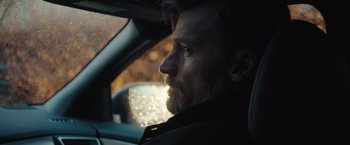 Movie still from “A Taste of Hunger” (2021), directed by Christoffer Boe – A man sitting in the driver's seat of a car looking out the window; Close Up shot, Over the shoulder angle