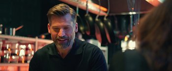 Movie still from “A Taste of Hunger” (2021), directed by Christoffer Boe – A man with a goatee and a beard smiling; Close Up shot, Over the shoulder angle