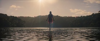 A woman standing in a body of water at sunset
