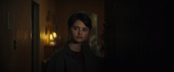 A woman standing in front of a door in a dark room