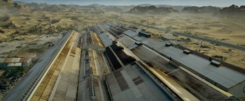 Movie still from “Expend4bles” (2023), directed by Scott Waugh – An aerial view of a train station in the middle of the desert; Extreme Wide shot, Overhead angle