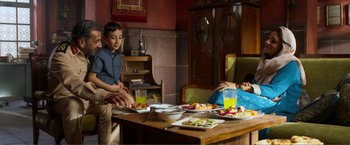 Movie still from “Expend4bles” (2023), directed by Scott Waugh – Two people sitting at a table with plates of food on it; Wide shot, High angle