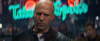 Movie still from “Expend4bles” (2023), directed by Scott Waugh – A man with a shaved head and a leather jacket; Close Up shot, Over the shoulder angle