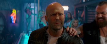 Movie still from “Expend4bles” (2023), directed by Scott Waugh – A man with a shaved head and a leather jacket; Close Up shot, Over the shoulder angle