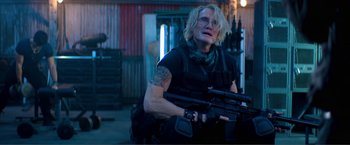 Movie still from “Expend4bles” (2023), directed by Scott Waugh – A woman holding a gun in a room; Medium shot, Over the shoulder angle