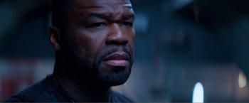 Movie still from “Expend4bles” (2023), directed by Scott Waugh – A man's face in a dark room; Close Up shot, Over the shoulder angle