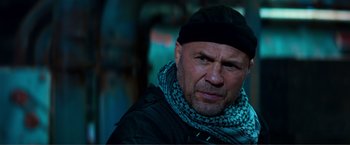 Movie still from “Expend4bles” (2023), directed by Scott Waugh – A person wearing a hat and a scarf; Close Up shot, Low angle