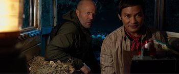 Movie still from “Expend4bles” (2023), directed by Scott Waugh – A man and a woman standing next to each other in the dark; Medium shot, Over the shoulder angle