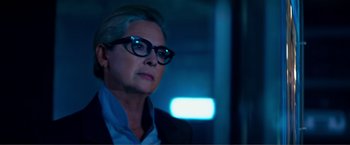 Movie still from “Expend4bles” (2023), directed by Scott Waugh – An older woman wearing glasses and a jacket; Close Up shot, Over the shoulder angle