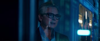 Movie still from “Expend4bles” (2023), directed by Scott Waugh – A woman wearing glasses and a suit is looking out a window; Close Up shot, Over the shoulder angle