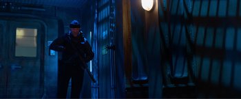 Movie still from “Expend4bles” (2023), directed by Scott Waugh – A man holding a gun while standing next to a building; Wide shot, Low angle