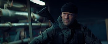 Movie still from “Expend4bles” (2023), directed by Scott Waugh – A man holding a gun in his hand; Close Up shot, Low angle