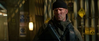 Movie still from “Expend4bles” (2023), directed by Scott Waugh – A person holding a gun; Close Up shot, Low angle