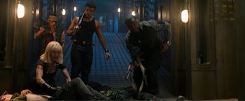 Movie still from “Expend4bles” (2023), directed by Scott Waugh – Two men in a room with guns and a dead body on the ground; Medium shot, High angle