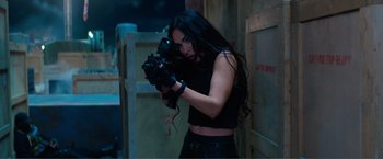 Movie still from “Expend4bles” (2023), directed by Scott Waugh – A woman holding a gun in her hands; Medium shot, Over the shoulder angle