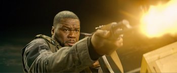 Movie still from “Expend4bles” (2023), directed by Scott Waugh – A person holding a gun; Close Up shot, Low angle