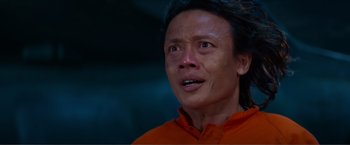 Movie still from “Expend4bles” (2023), directed by Scott Waugh – A man in an orange shirt looking up at the sky; Close Up shot, Low angle