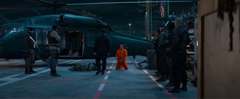 Movie still from “Expend4bles” (2023), directed by Scott Waugh – A man in an orange jumpsuit standing in front of an airplane; Wide shot, High angle