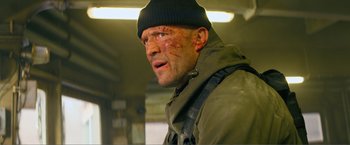 Movie still from “Expend4bles” (2023), directed by Scott Waugh – A person wearing a jacket and a hat; Close Up shot, Low angle