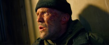 Movie still from “Expend4bles” (2023), directed by Scott Waugh – A person wearing a hat and a jacket; Close Up shot, Low angle
