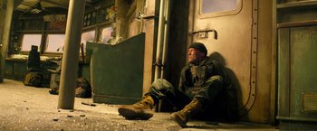 Movie still from “Expend4bles” (2023), directed by Scott Waugh – A man sitting on the floor of a train car; Wide shot, Low angle
