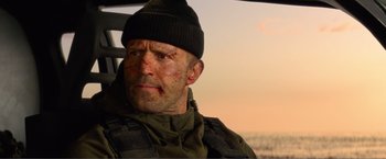 Movie still from “Expend4bles” (2023), directed by Scott Waugh – A person wearing a hat and a jacket; Close Up shot, Over the shoulder angle