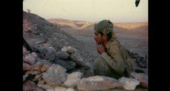 Movie still from “Explorer” (2022), directed by Matthew Dyas – A man sitting on top of a rocky hill; Medium shot, High angle