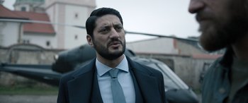 Movie still from “Extraction II” (2023), directed by Sam Hargrave – A person wearing a suit and tie; Close Up shot, Over the shoulder angle