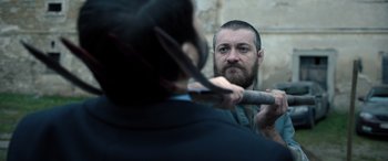 Movie still from “Extraction II” (2023), directed by Sam Hargrave – A man with a beard is holding a pair of scissors; Close Up shot, Over the shoulder angle