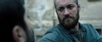 Movie still from “Extraction II” (2023), directed by Sam Hargrave – A person with a beard; Close Up shot, Over the shoulder angle