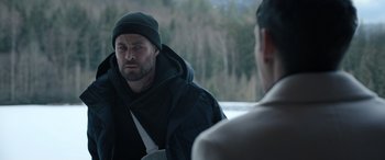 Movie still from “Extraction II” (2023), directed by Sam Hargrave – A man wearing a black jacket and a hat; Medium shot, Over the shoulder angle