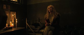 Movie still from “Extraction II” (2023), directed by Sam Hargrave – A woman sitting on top of a bed in a dark room; Medium shot, Low angle