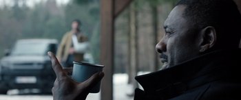 Movie still from “Extraction II” (2023), directed by Sam Hargrave – A man holding a cup of coffee in his hand; Close Up shot, Over the shoulder angle