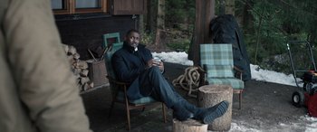 Movie still from “Extraction II” (2023), directed by Sam Hargrave – A man sitting on a chair outside in the snow; Wide shot, High angle