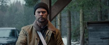 Movie still from “Extraction II” (2023), directed by Sam Hargrave – A person wearing a jacket and hat; Medium shot, Over the shoulder angle