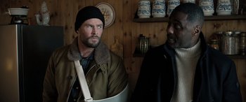 Movie still from “Extraction II” (2023), directed by Sam Hargrave – A man with a broken arm standing next to another man; Medium shot, Over the shoulder angle