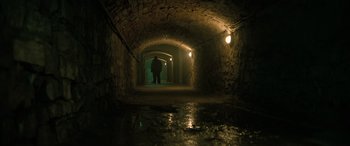 Movie still from “Extraction II” (2023), directed by Sam Hargrave – A person holding an umbrella in a dark tunnel; Wide shot, High angle