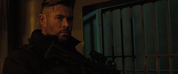 Movie still from “Extraction II” (2023), directed by Sam Hargrave – A person holding a gun in a dark room; Close Up shot, Low angle