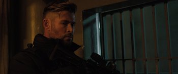 Movie still from “Extraction II” (2023), directed by Sam Hargrave – A person holding a gun in a room; Close Up shot, Over the shoulder angle