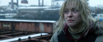 Movie still from “Extraction II” (2023), directed by Sam Hargrave – A woman in a white jacket is standing outside; Close Up shot, Over the shoulder angle