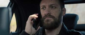 Movie still from “Extraction II” (2023), directed by Sam Hargrave – A man with a beard is talking on a cell phone; Close Up shot, High angle