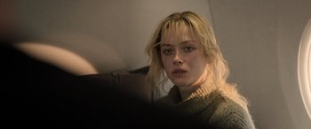 Movie still from “Extraction II” (2023), directed by Sam Hargrave – A young woman with blonde hair and a sweater; Close Up shot, Over the shoulder angle