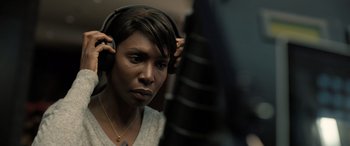 Movie still from “Extraction II” (2023), directed by Sam Hargrave – A woman wearing headphones while standing in a recording studio; Close Up shot, Over the shoulder angle